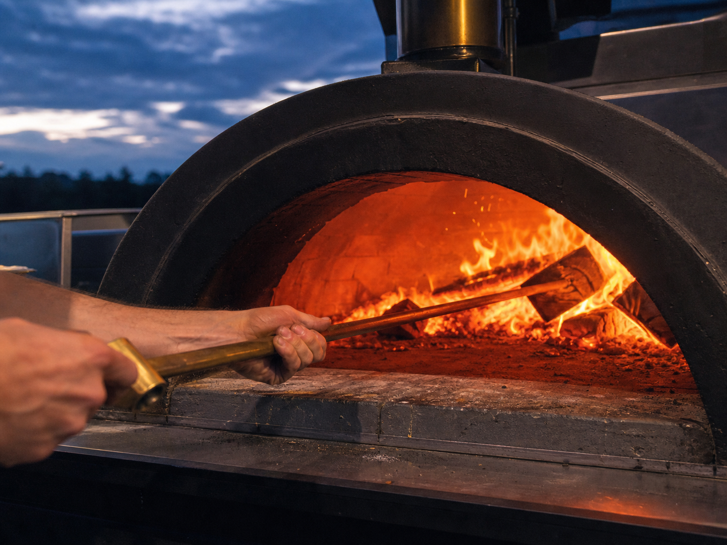 En pizzabagare ordnar veden i en glödande vedugn